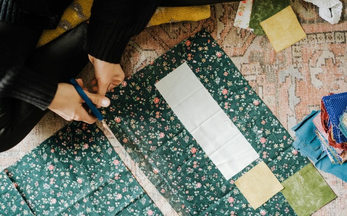 A person is cutting a piece of flower print fabric.